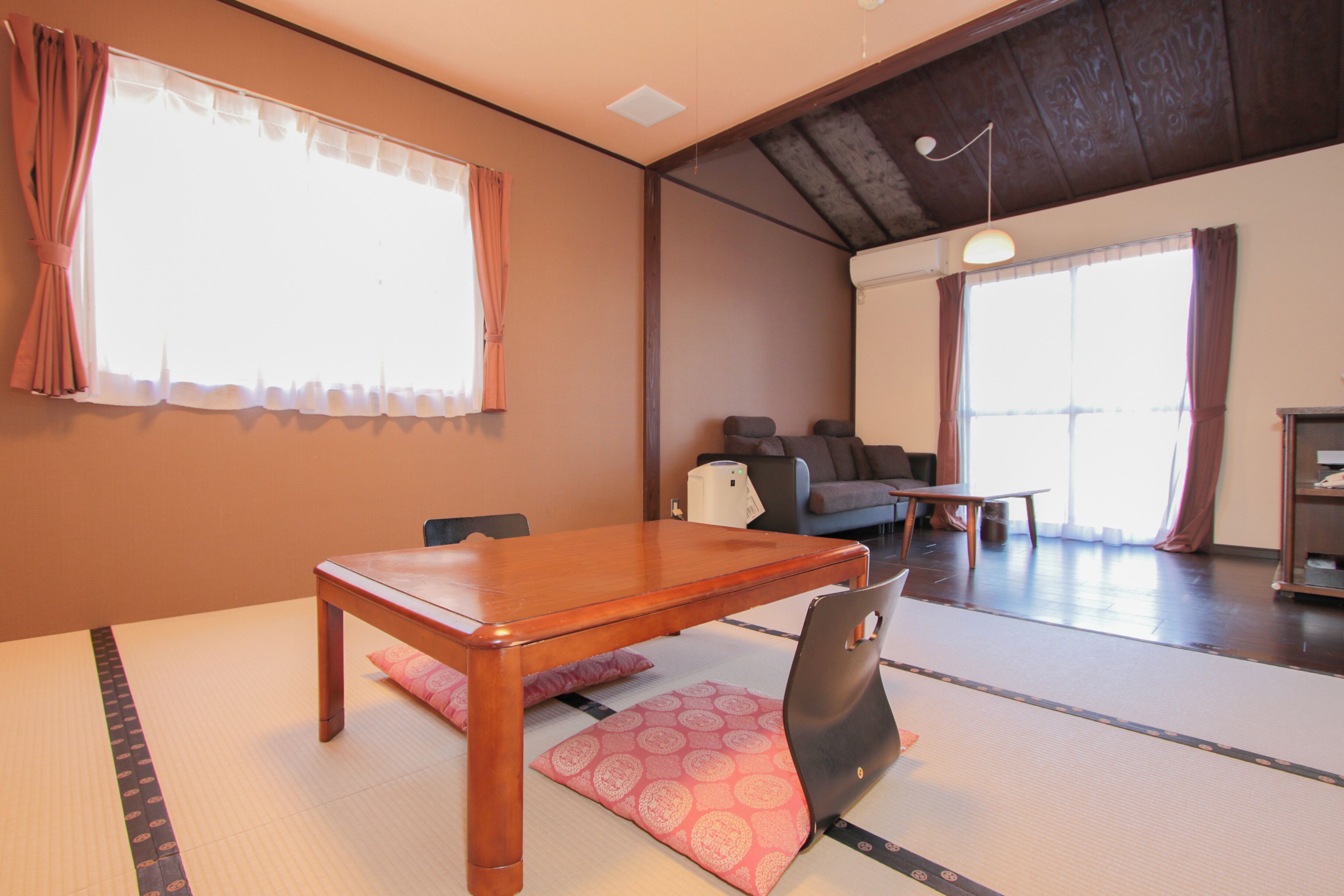 Un espacio tradicional con tatami, una mesa de madera, cojines y un sofá.