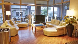 A spacious living room with a large TV, comfortable seating, and a view of the outside. - Ooedo Onsen Monogatari Kimitsu no Mori (Kimitsu)