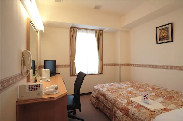 A hotel room with a bed, a desk with a telephone and a hairdryer, a chair, a window with curtains, and a framed picture on the wall. - Life Inn Katsuta Station West (Hitachinaka)