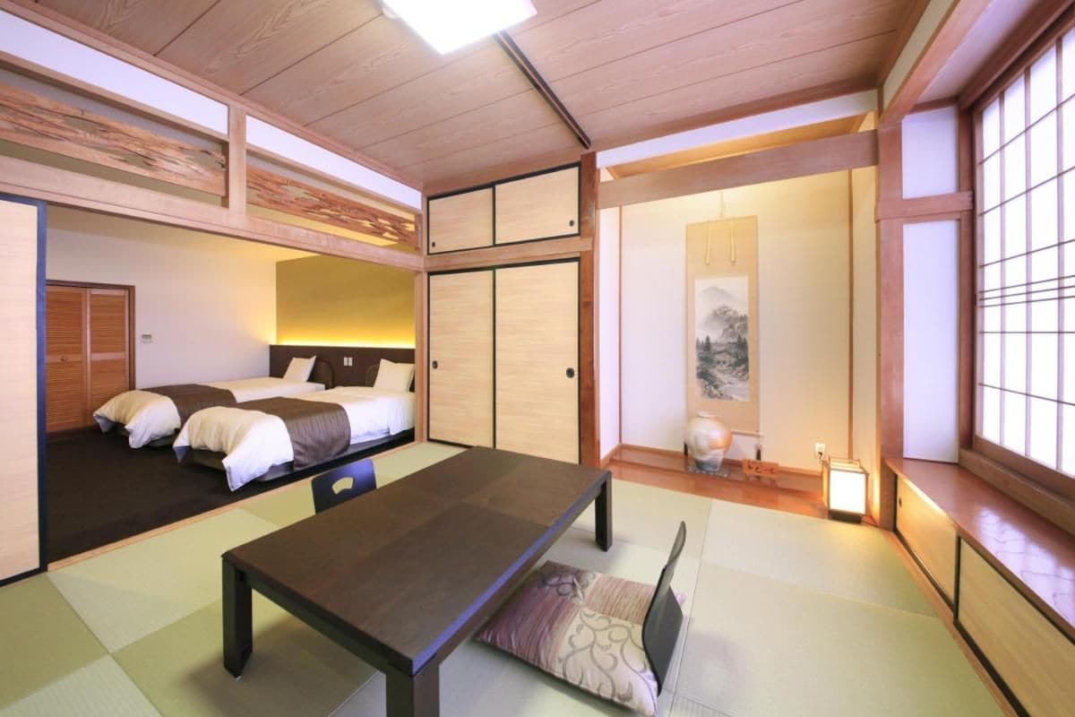 A traditional Japanese-style room with tatami flooring, a low table, and a bed with futon mattresses.