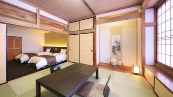 A traditional Japanese-style room with tatami flooring, a low table, and a bed with futon mattresses.