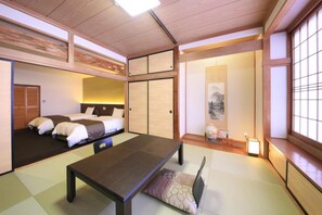 A traditional Japanese-style room with tatami flooring, a low table, and a bed with futon mattresses. - Nanpeidai Onsen Hotel (Nakagawa)