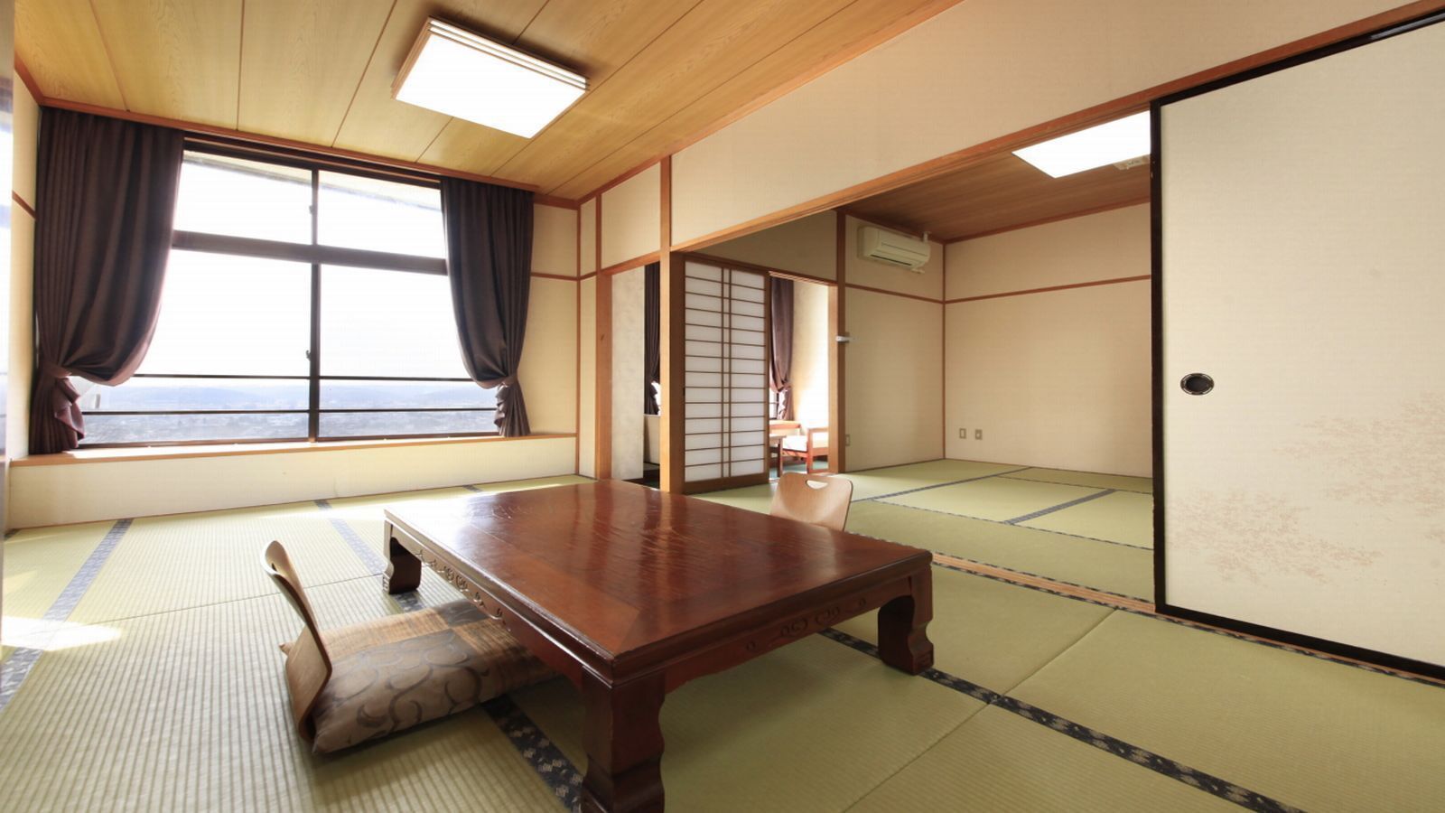 Una habitación japonesa tradicional con suelo de tatami, una mesa de madera y puertas correderas.