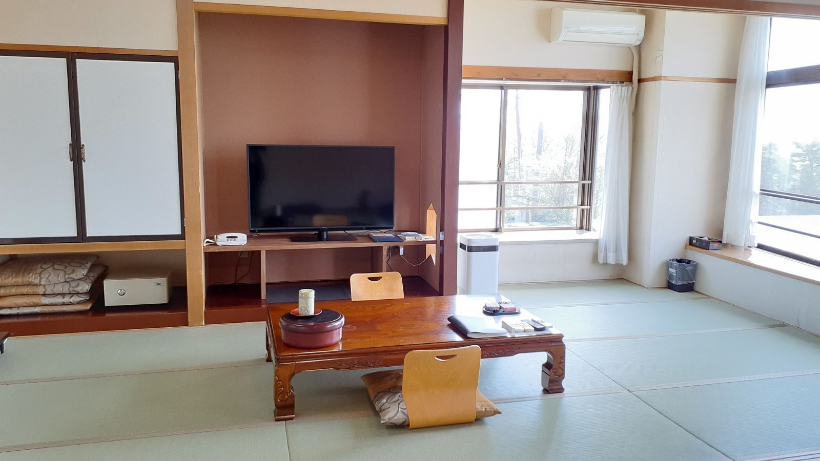 Una habitación japonesa tradicional con suelo de tatami, televisor, mesa de madera y puerta corredera.