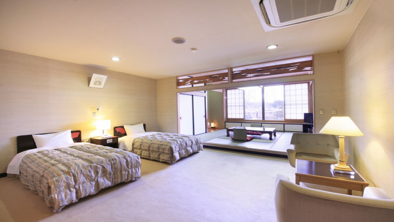 Habitación de hotel con dos camas, un escritorio, una silla, una ventana y una puerta corredera tradicional japonesa.