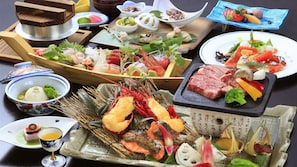 A variety of seafood and meat dishes, including lobster, salmon, and beef, arranged on a table.