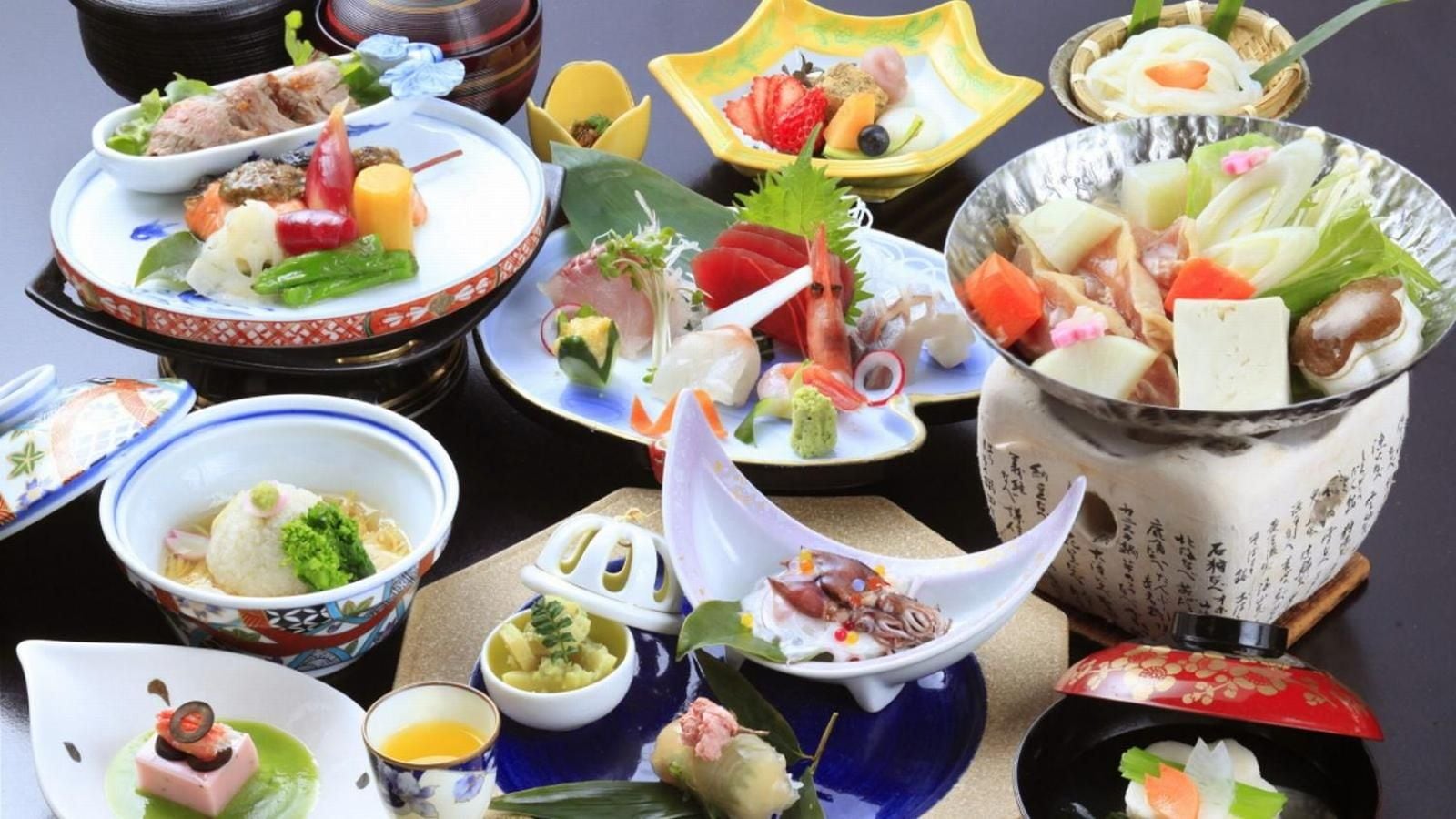 A variety of dishes arranged on a table, including bowls, plates, and a hot pot.