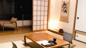 A traditional Japanese room with tatami flooring, a low wooden table, a sofa, and a sliding door with a shoji screen. - Hakone Kuoritei (Hakone)