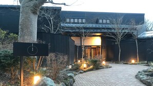 A modern building with a paved entrance, a signboard, and a well-lit pathway leading to the entrance. - Hakone Kuoritei (Hakone)