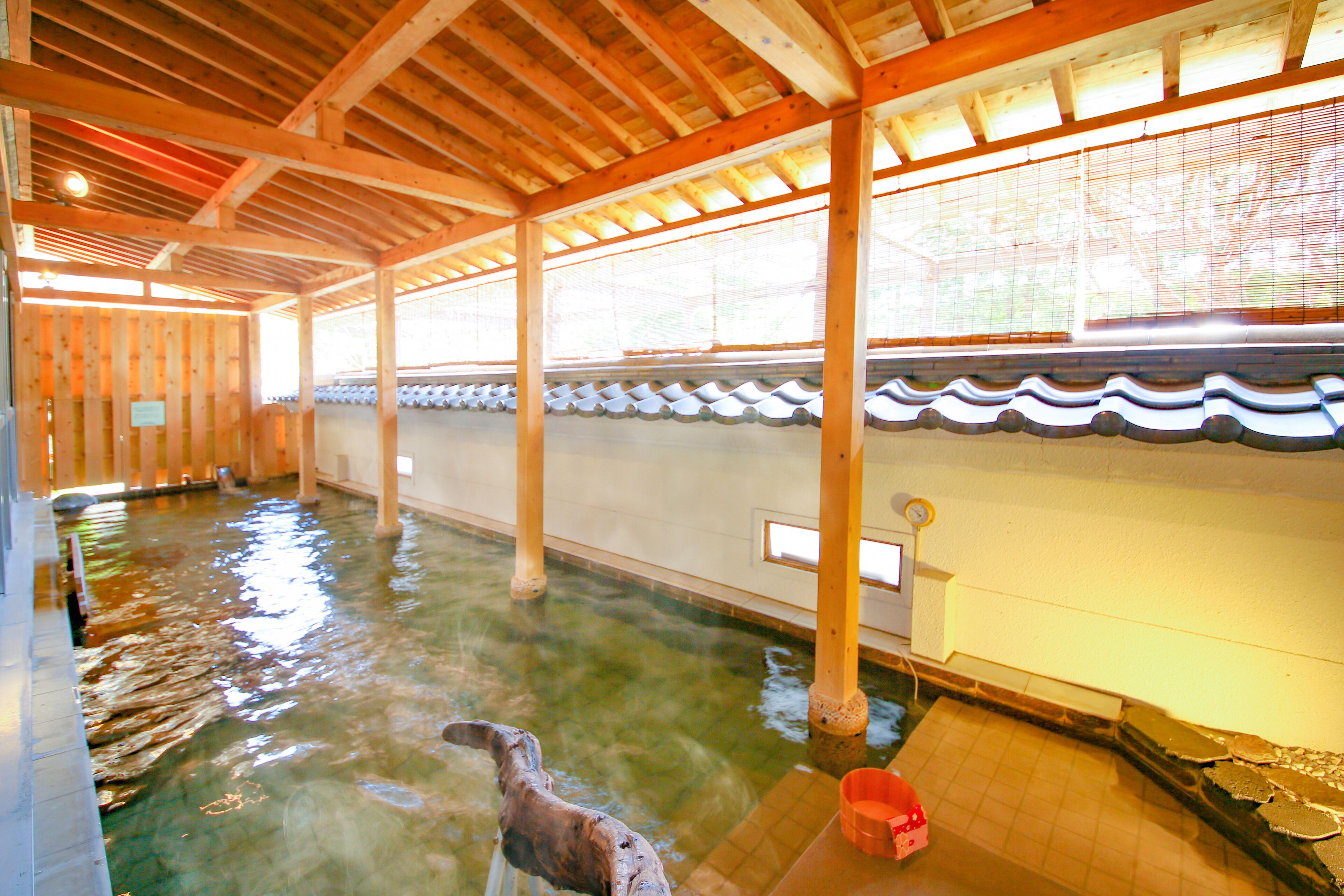 An indoor swimming pool with wooden beams and tiled walls.