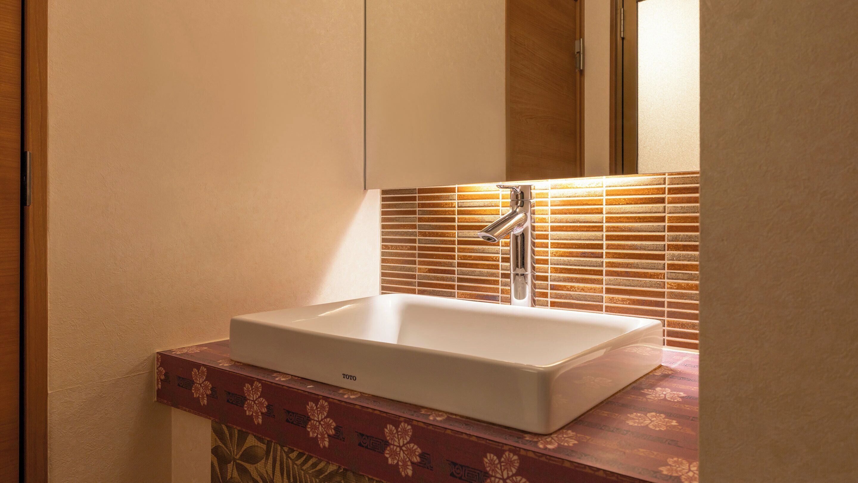 A bathroom with a white sink, a mirror, and a tiled backsplash.