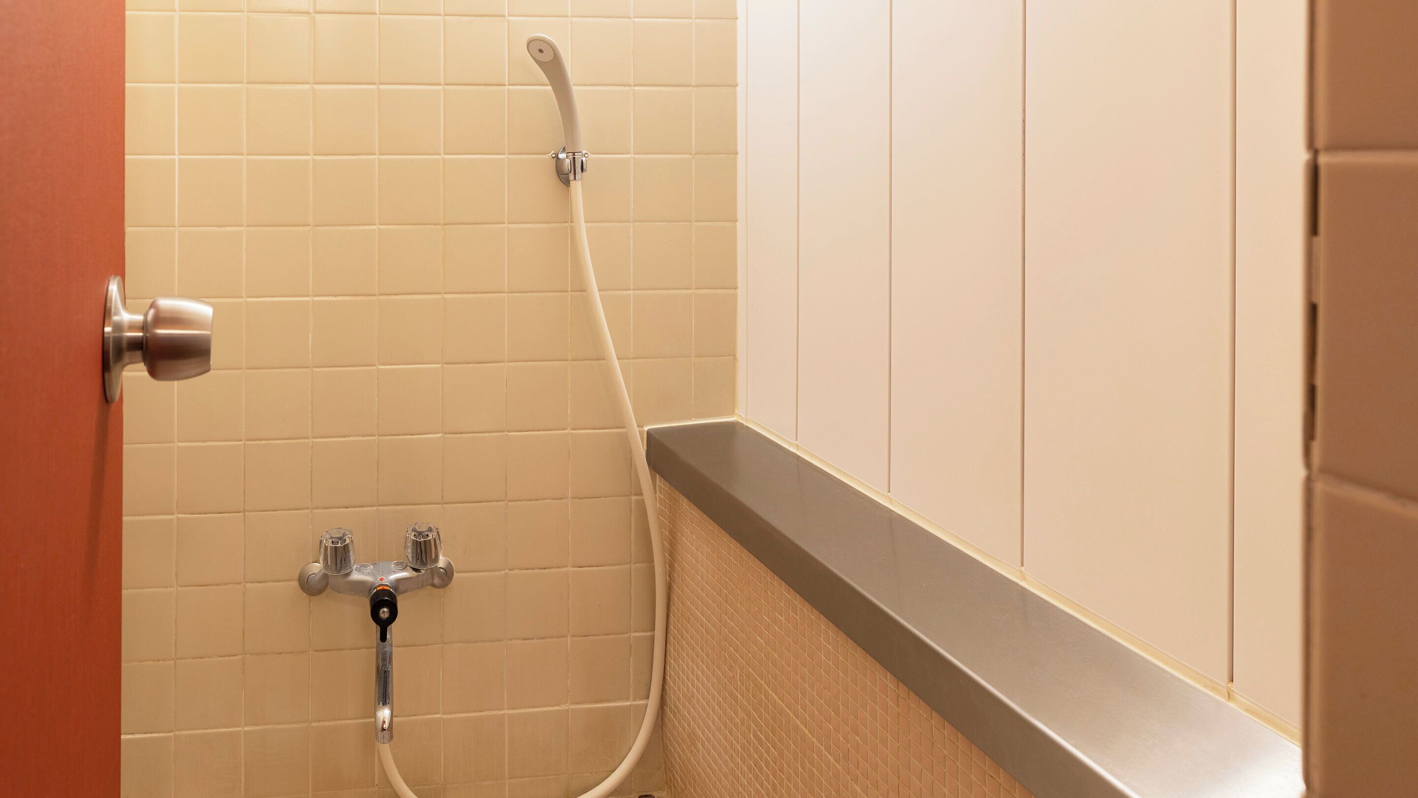A bathroom with a shower, a towel rack, and a door.
