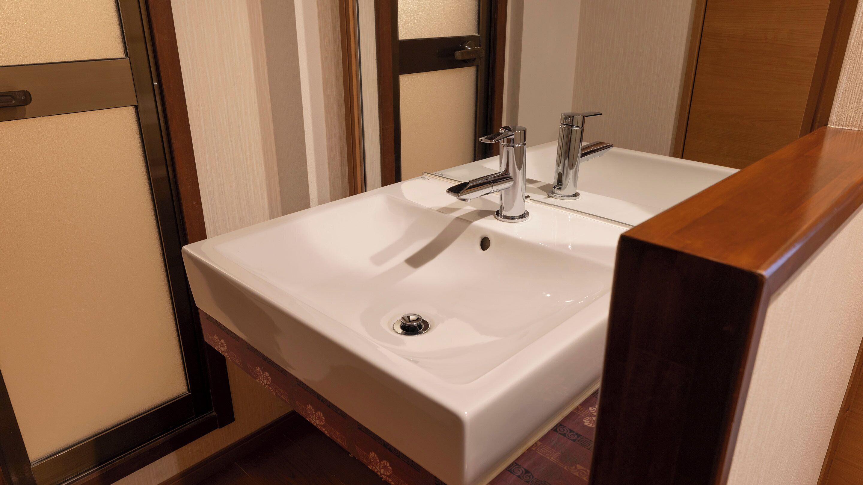 A bathroom with a white sink, chrome faucet, and a mirror.