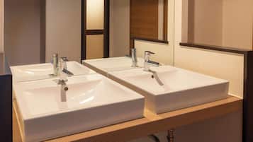 A bathroom with two white sinks, each with a modern faucet, and a mirror above them.