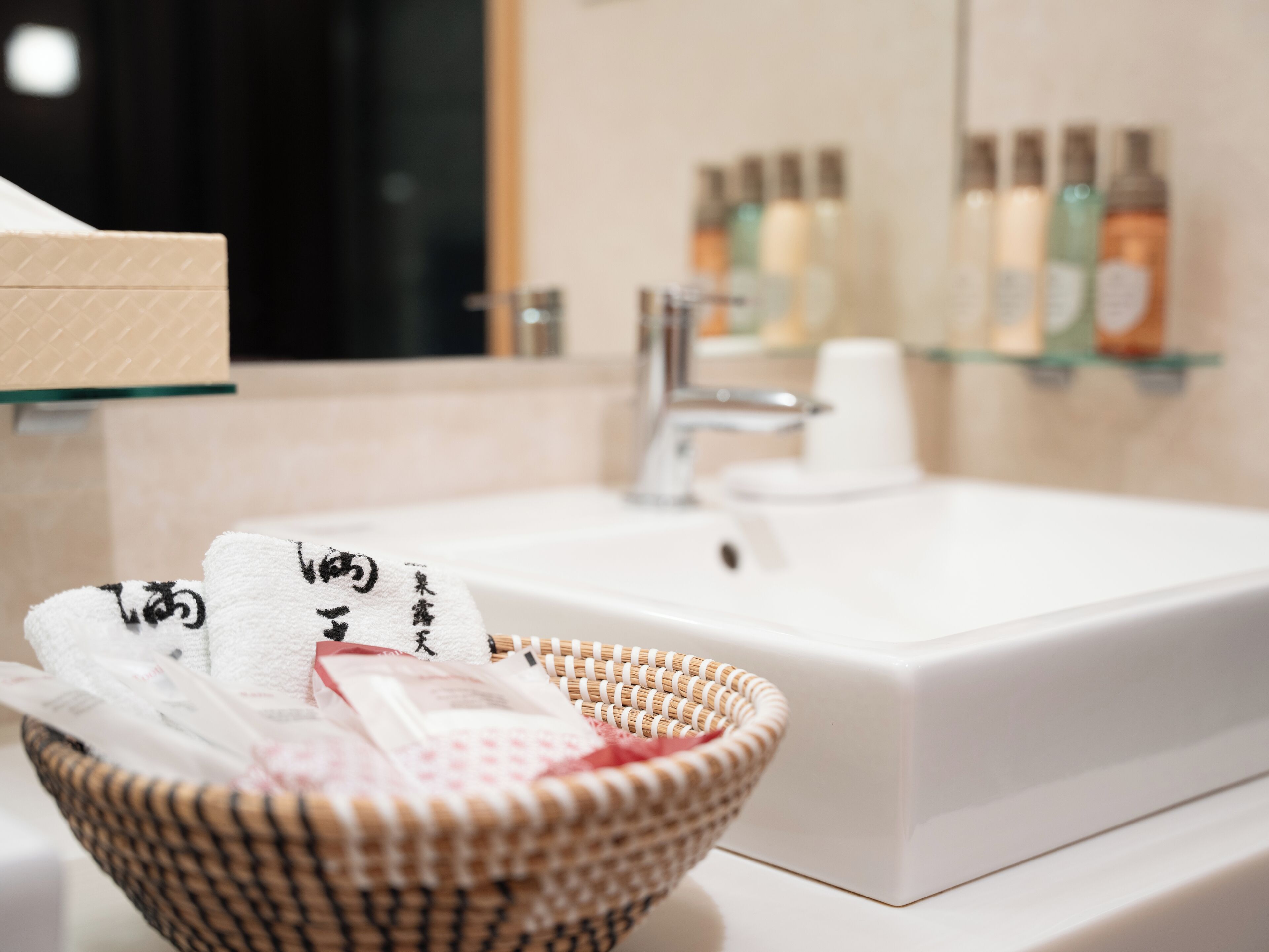 Ein Badezimmer mit einem weißen Waschbecken, einem Spiegel und einer Glasablage mit Pflegeprodukten.