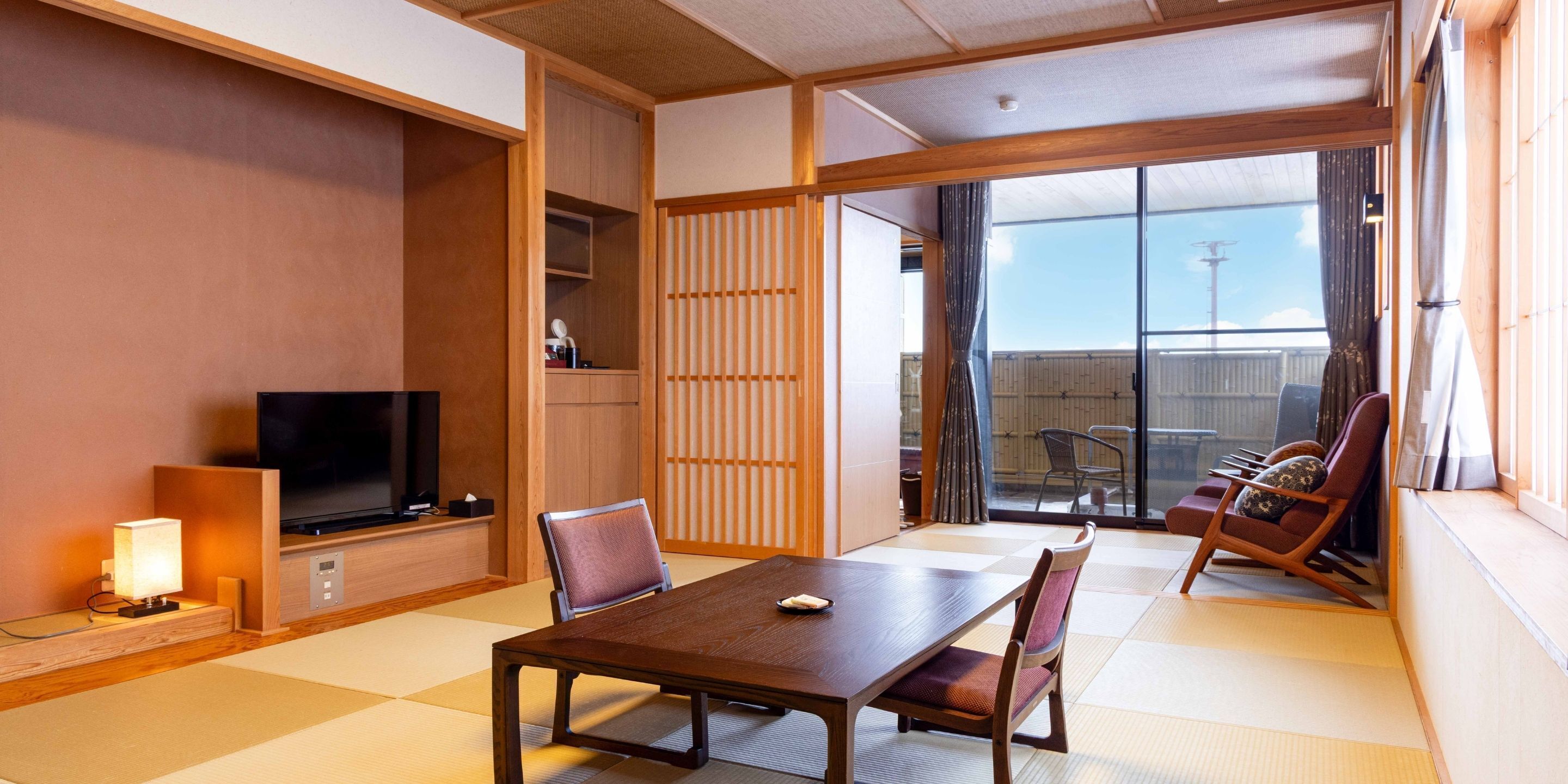 A traditional Japanese room with tatami flooring, a low table, and seating.