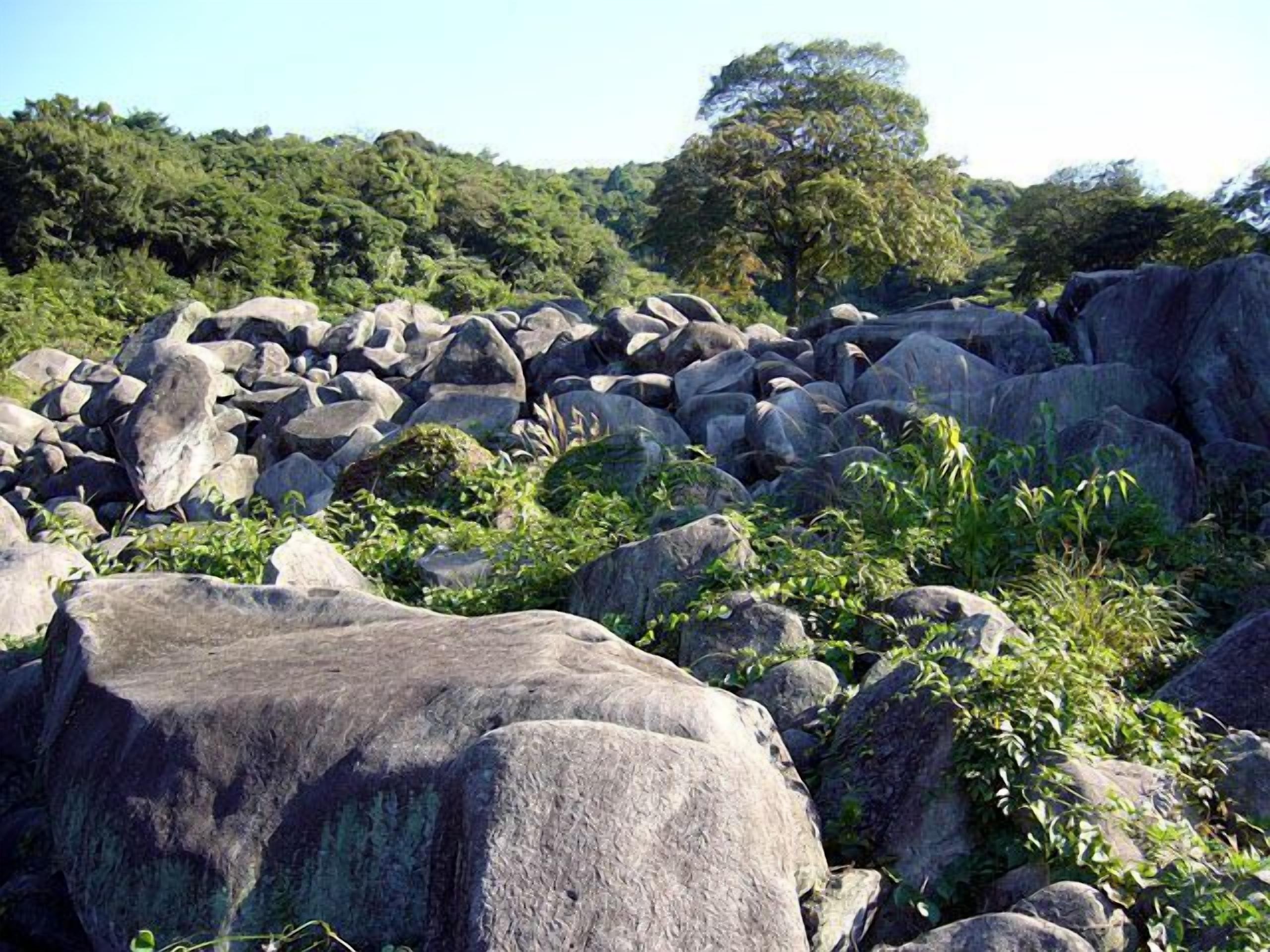 A rocky landscape with large boulders and dense greenery.