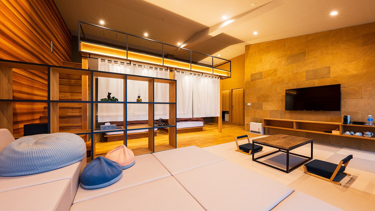 A modern living room with a sofa, a coffee table, a TV mounted on the wall, and a wooden partition with a window.
