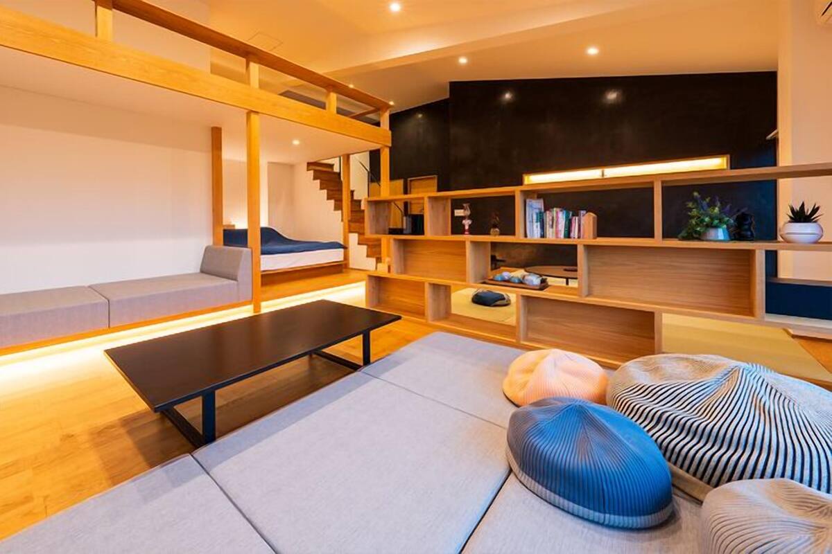 Un salon moderne comprenant un canapé, une table basse, une bibliothèque et un escalier.
