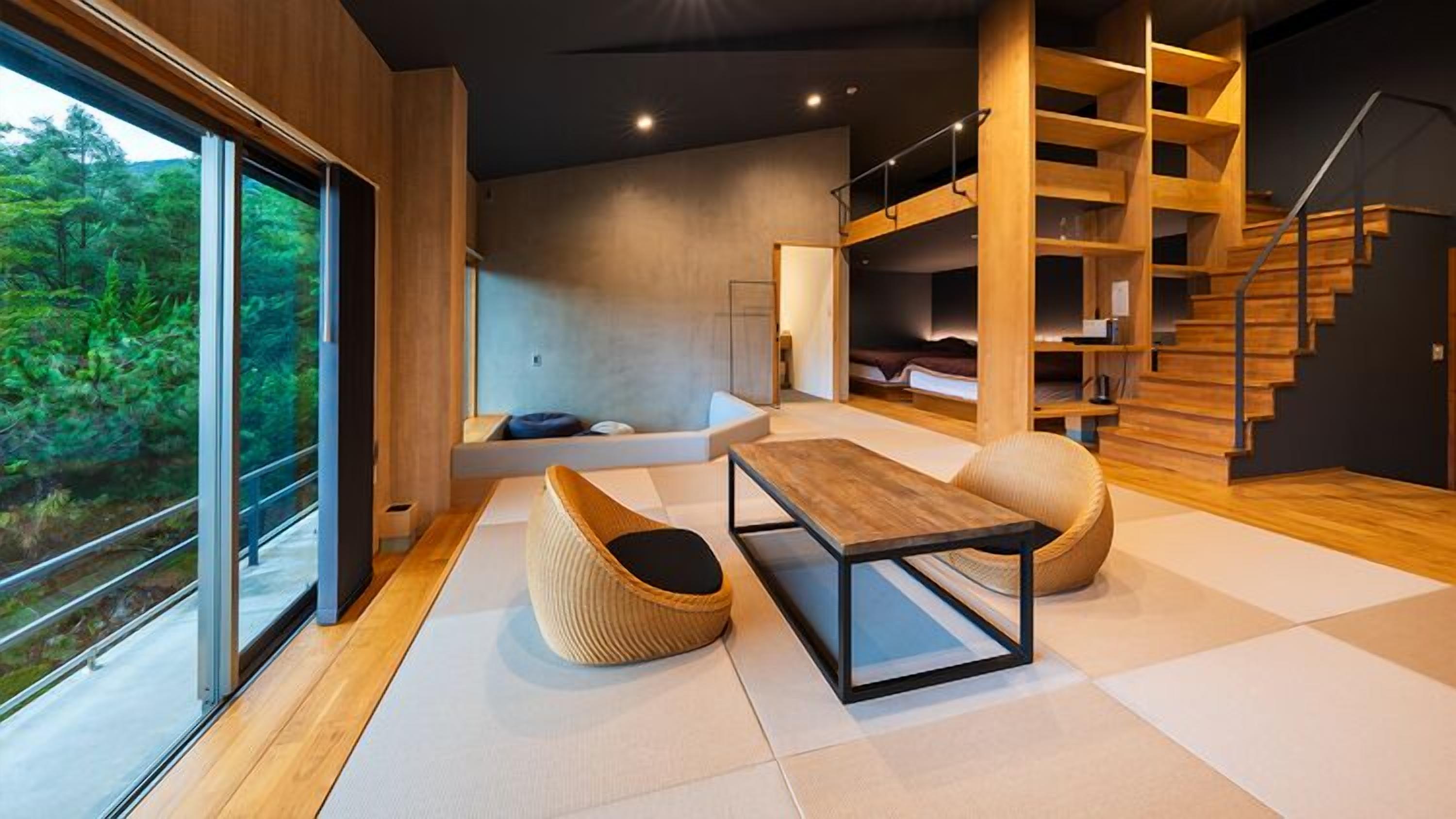 A modern interior with a large window, a wooden staircase, and a seating area.