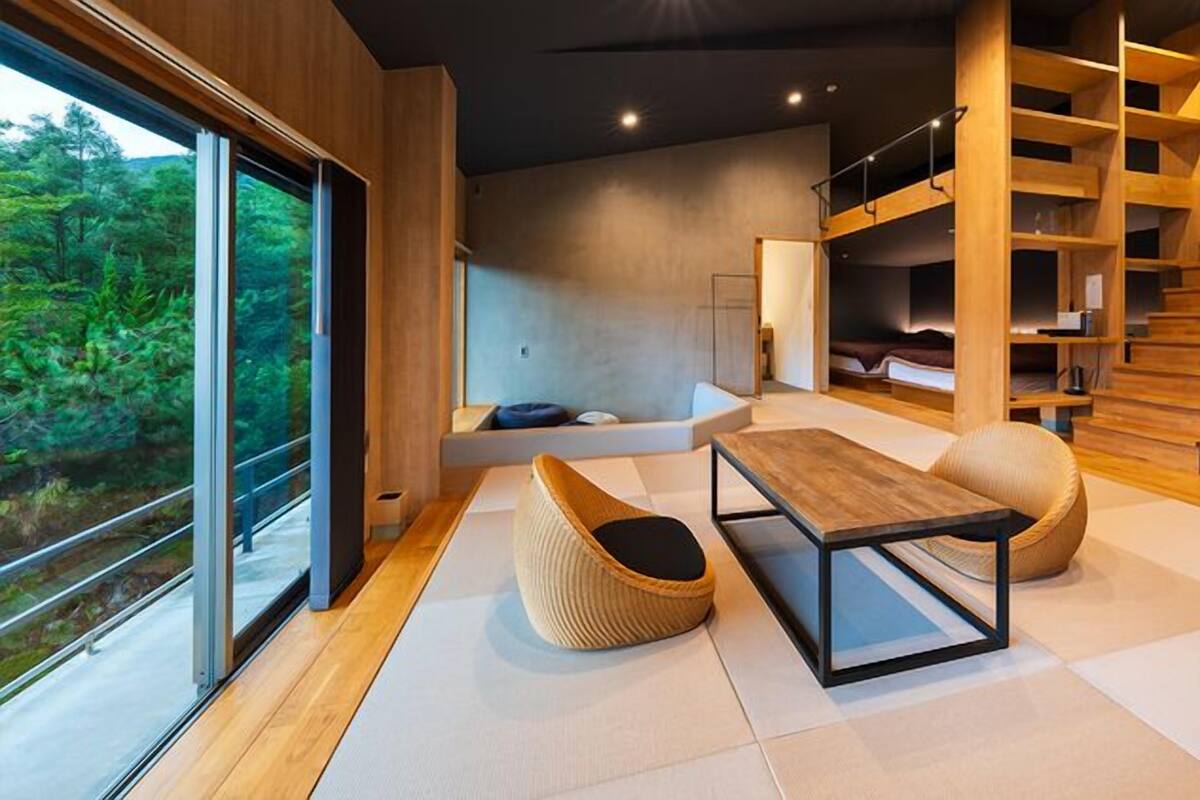 Un intérieur moderne avec une grande fenêtre, un escalier en bois et un coin salon.