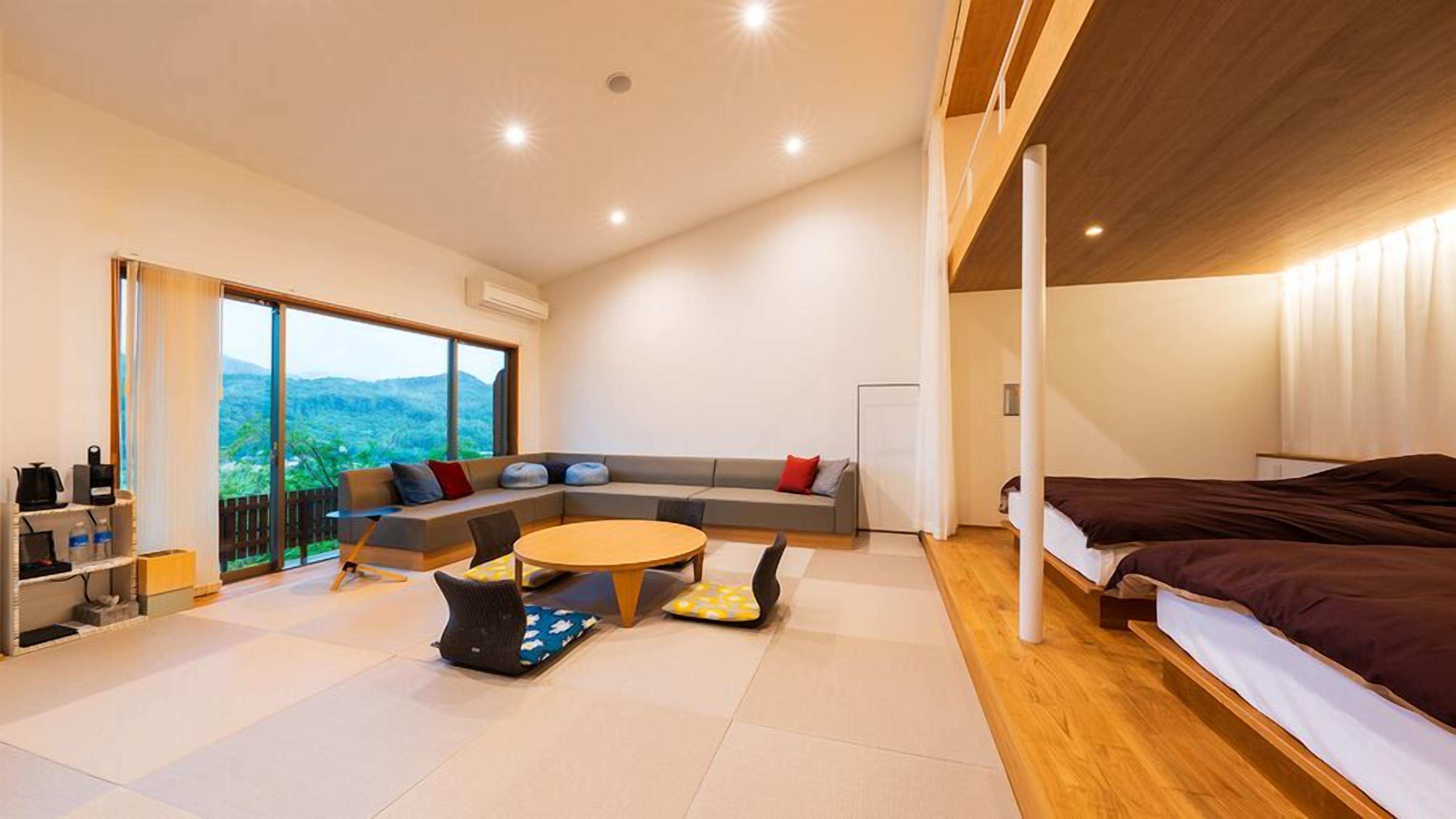 A modern room with a large window, a sofa, a round table, and a bed.