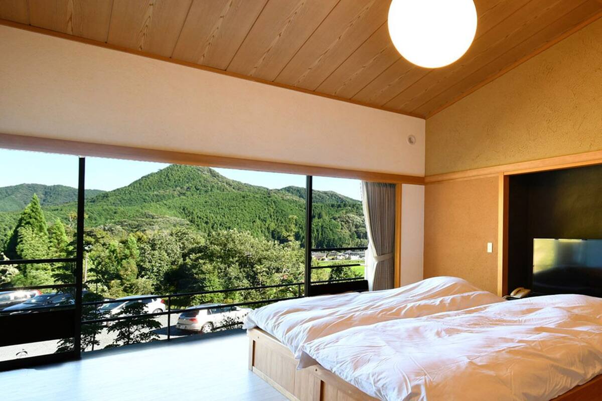 Une chambre avec une grande fenêtre, un lit et un téléviseur.