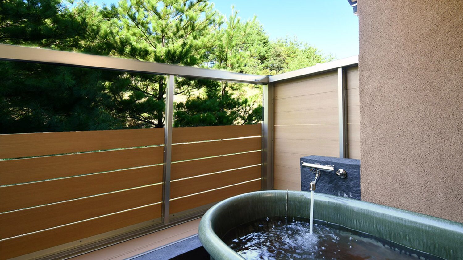 A spa area with a hot tub, wooden slatted wall, and a stone wall.