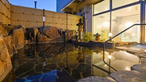 A stone hot spring with a wooden fence and a traditional Japanese lantern. - Sun Green Kikugawa (Shimonoseki)