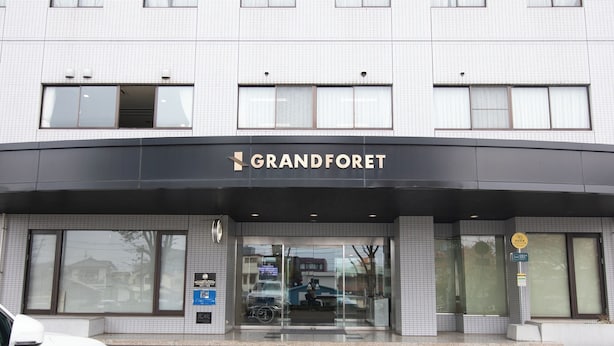 L'ingresso di un hotel con un cartello che riporta 'GRANDFORET' e una porta in vetro.