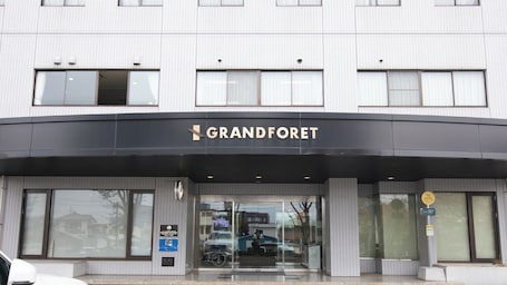 A hotel entrance with a sign reading 'GRANDFORET' and a glass door.