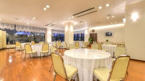 Una sala conferenze con tavoli rotondi, sedie e ampie finestre.