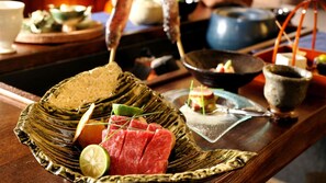 A traditional Japanese meal setup with a woven basket containing sliced meat, lime, and herbs. - Kyoya (Takayama)