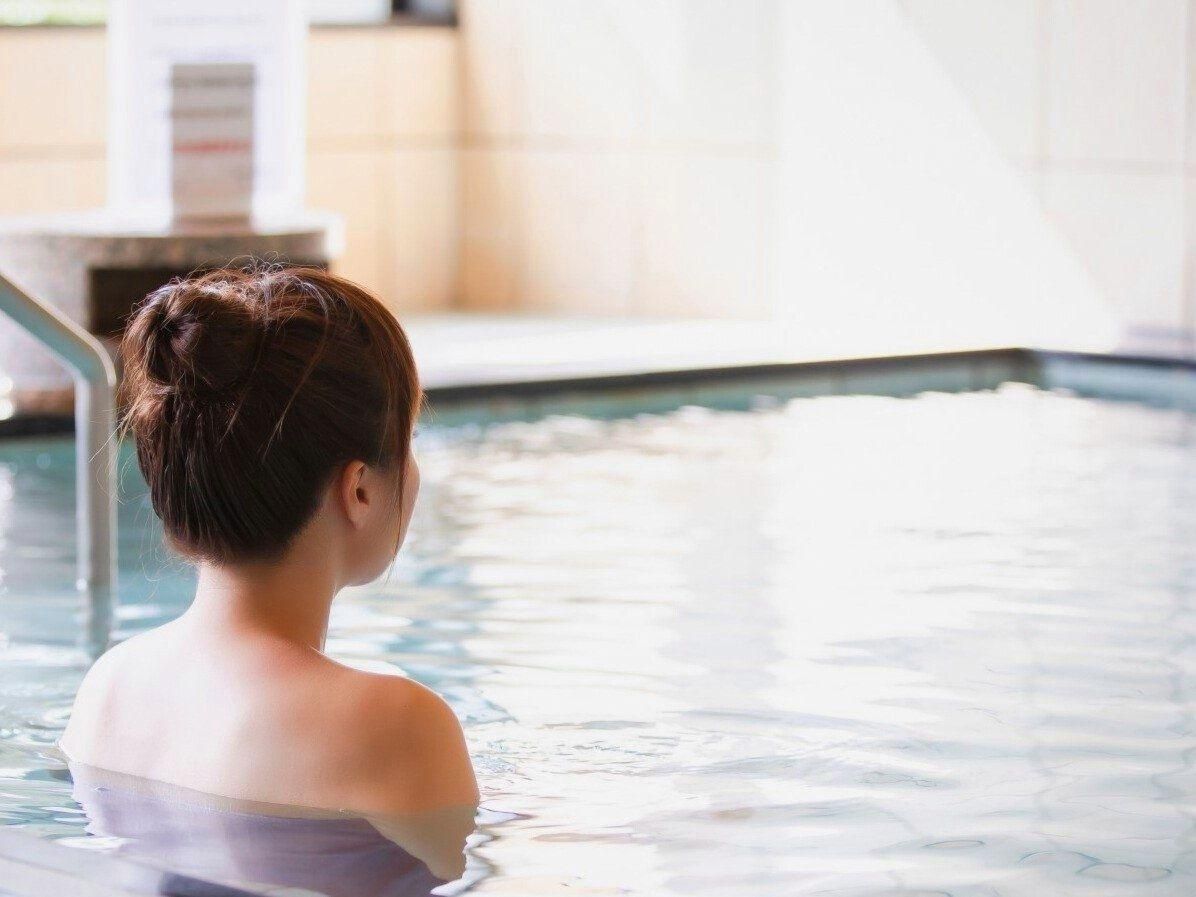 A person in a swimming pool with a tiled wall in the background.