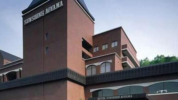Een hotel met een opvallende toren en een bord waarop 'SUNSHINE AOVAMA' staat.