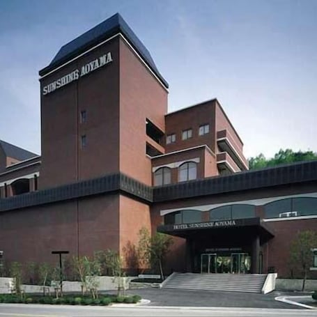A hotel with a prominent tower and a sign reading 'SUNSHINE AOVAMA.'