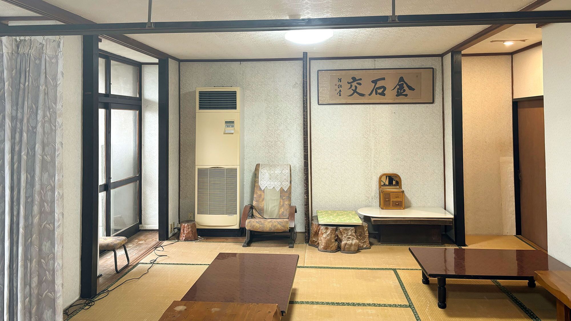 Une pièce de style japonais traditionnel, avec un sol recouvert de tatamis, un paravent en papier de riz (shoji), un futon servant de lit, une armoire en bois et une petite table.