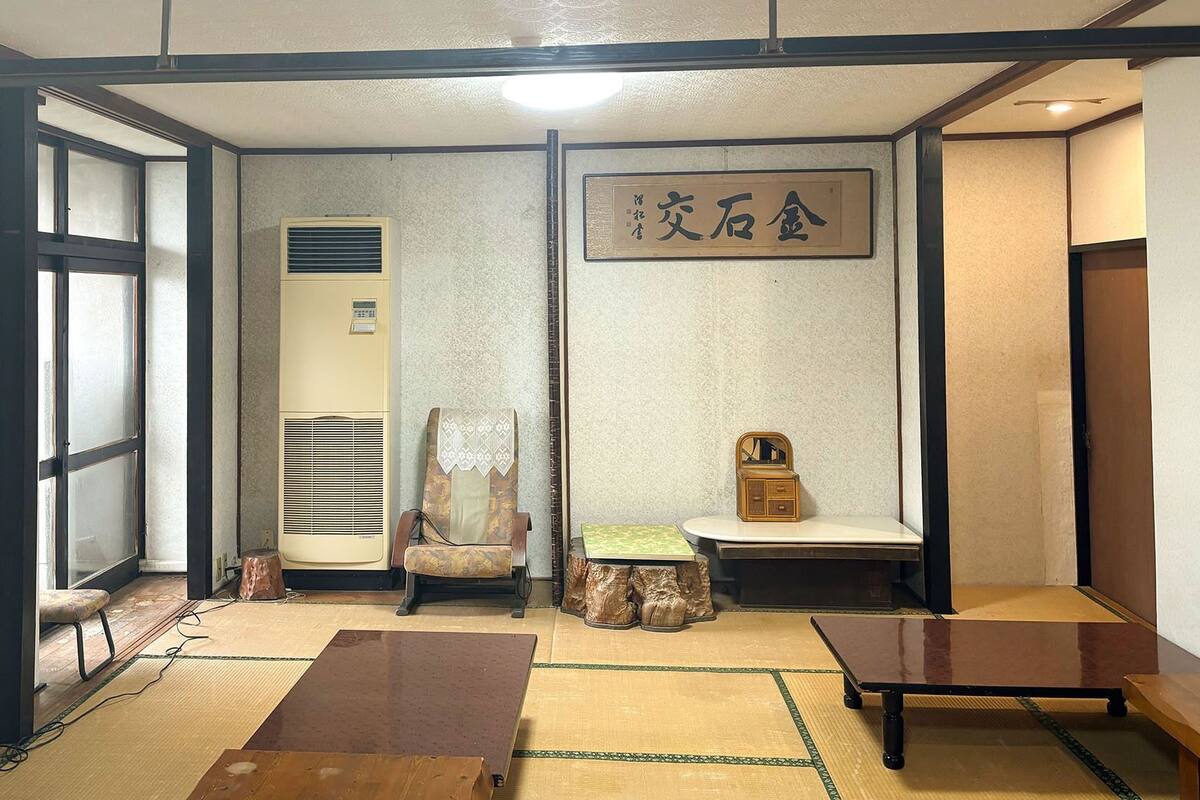 Ein traditioneller japanischer Raum mit Tatami-Bodenbelag, Shoji-Schirm, Futon-Bett, Holzschrank und einem kleinen Tisch.