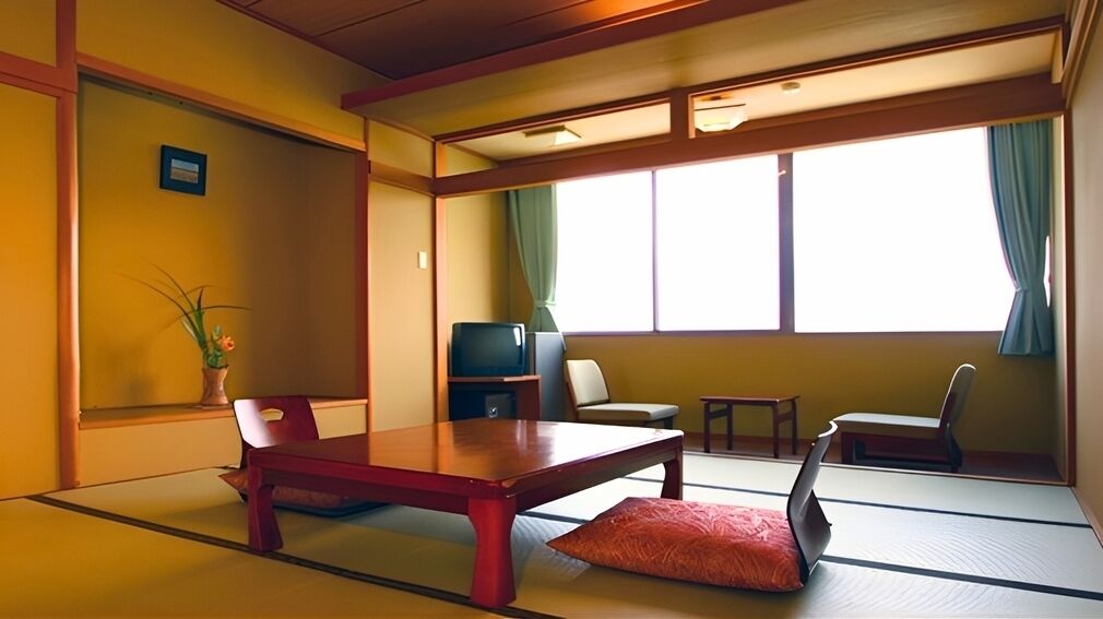 Quarto japonês tradicional com tatames, uma mesa baixa, uma televisão e uma janela com cortinas.