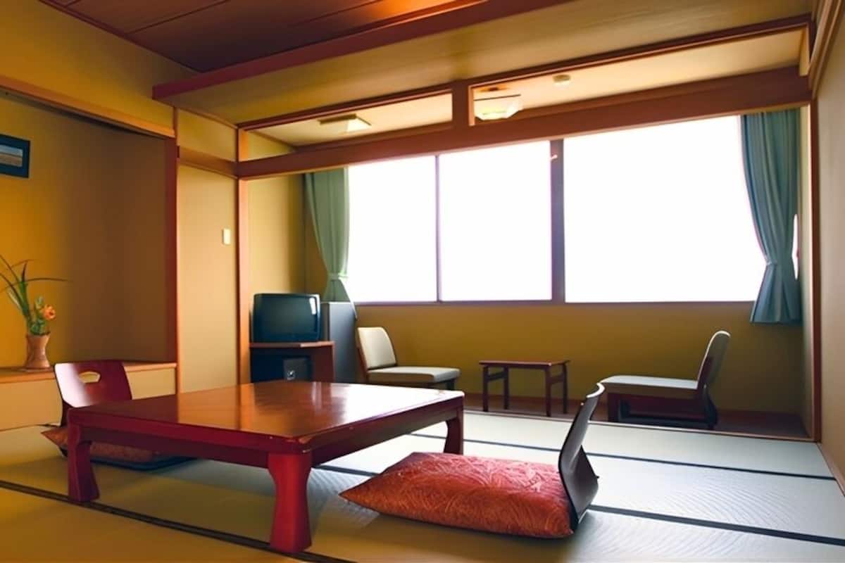 A traditional Japanese room with tatami flooring, a low table, a television, and a window with curtains.