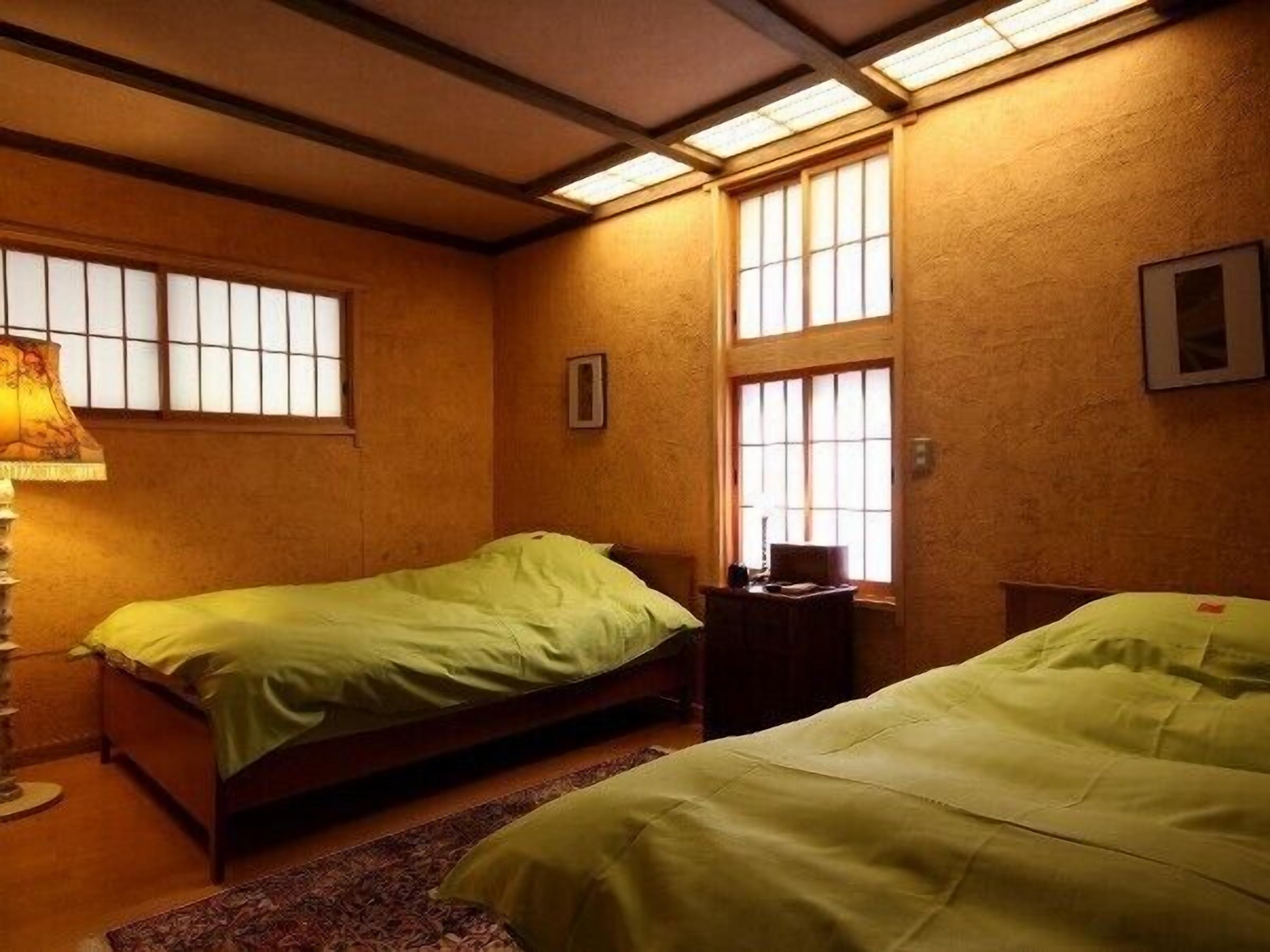 A room with two beds, a desk, and a lamp.