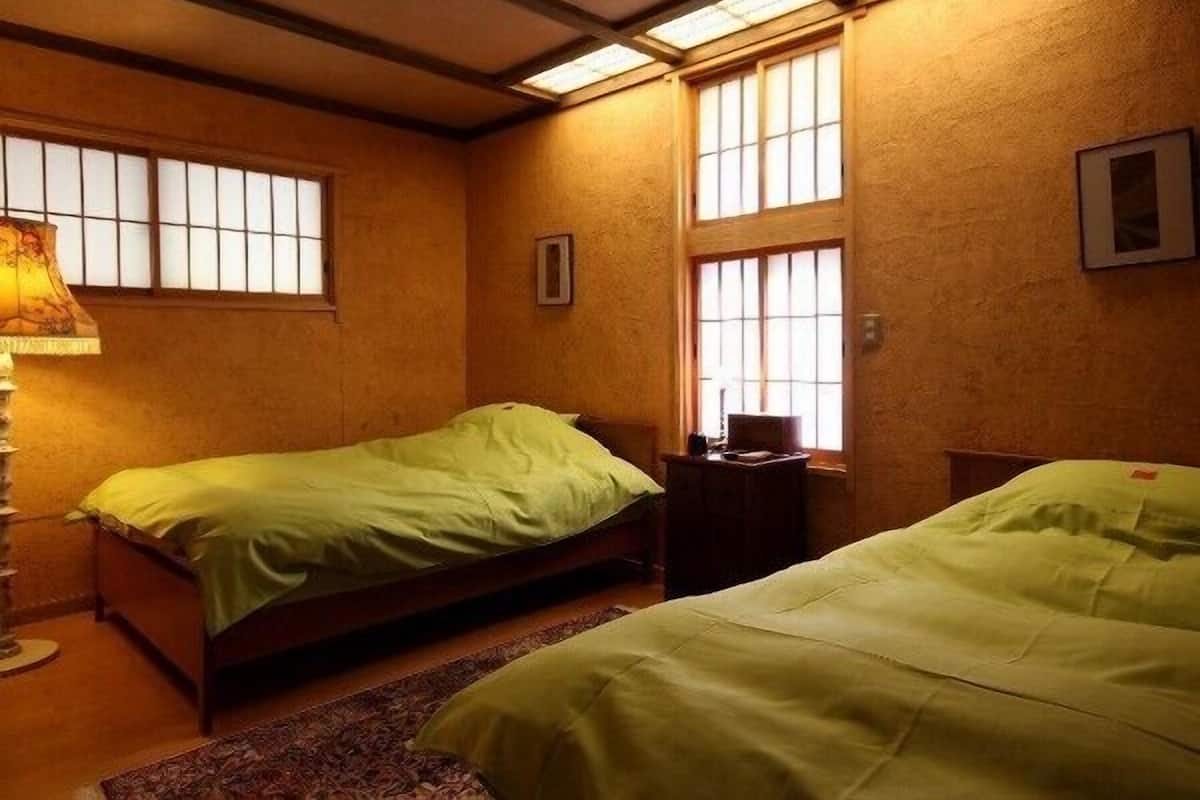Una habitación con dos camas, un escritorio y una lámpara.
