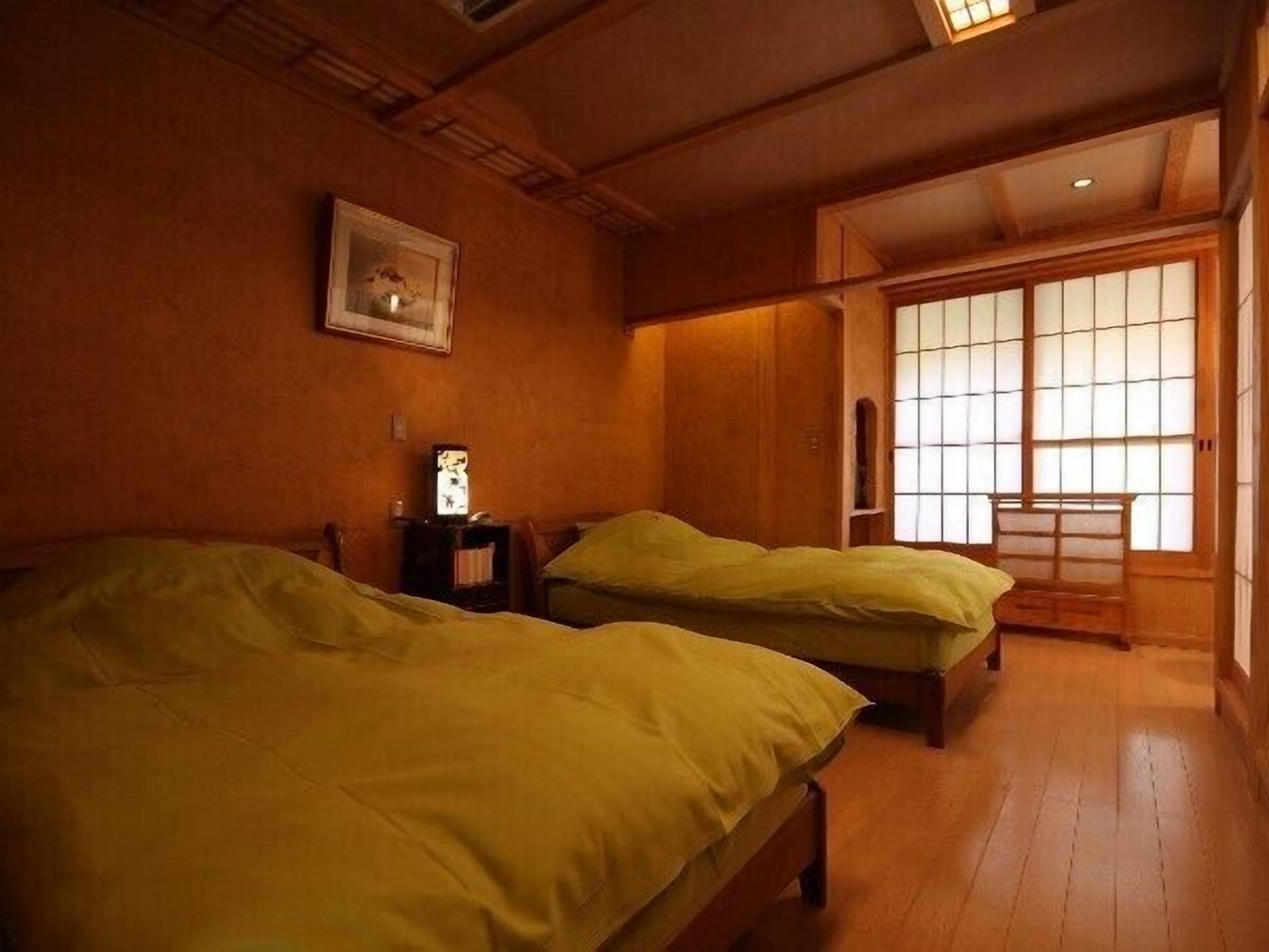 A traditional Japanese-style room with two beds, wooden flooring, and sliding doors.