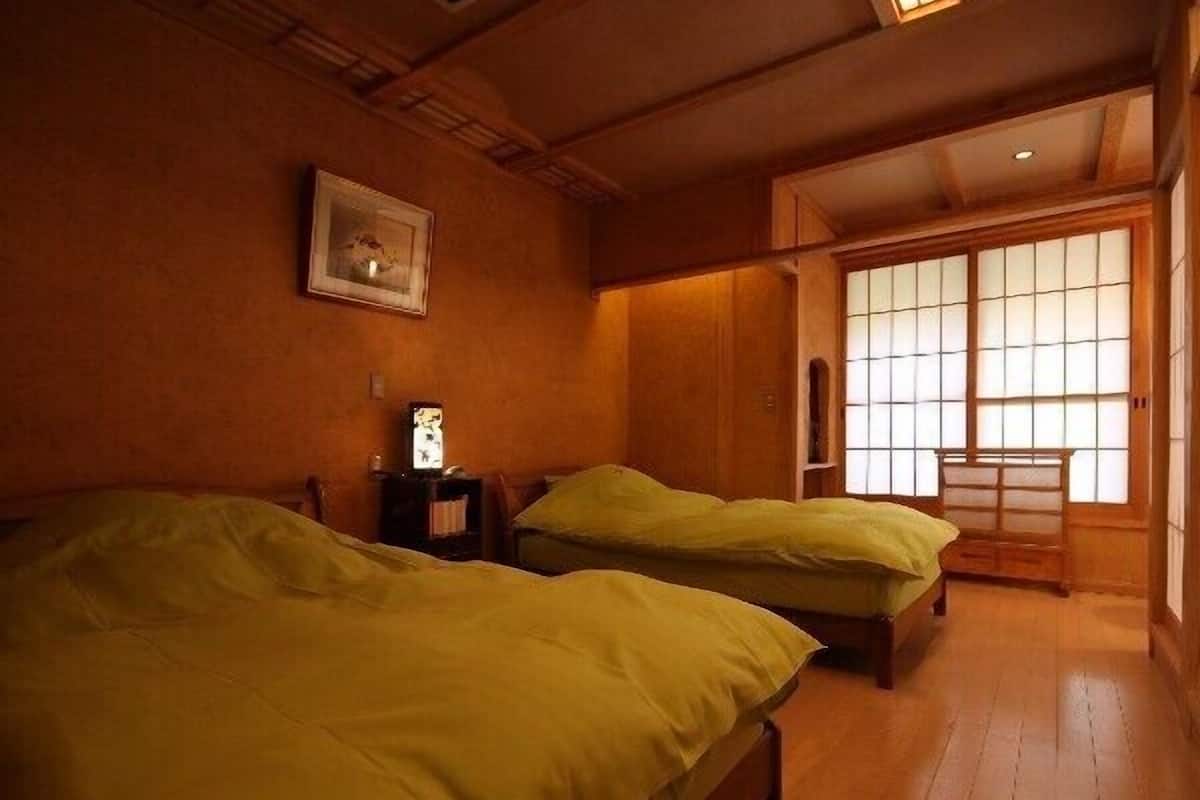 Una habitación tradicional japonesa con dos camas, suelo de madera y puertas correderas.