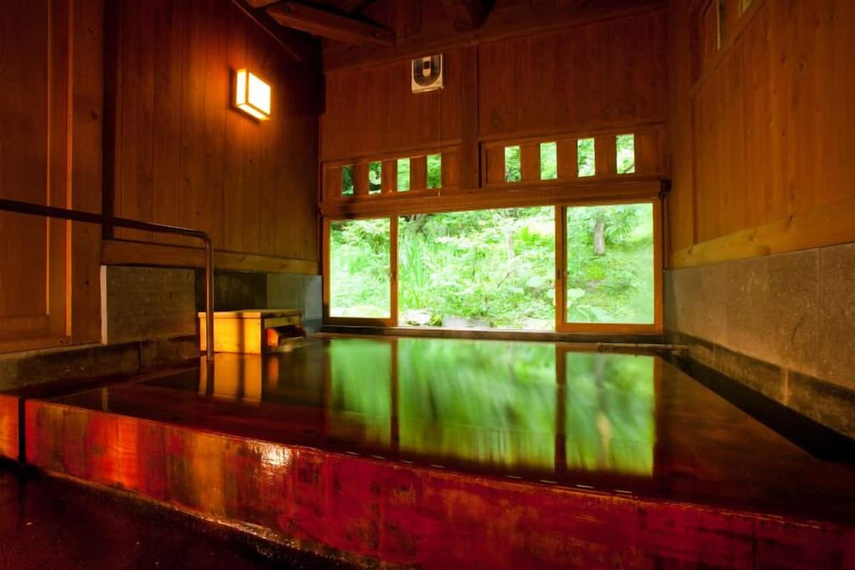 Un interior de madera con un ventanal grande, un banco y una pequeña mesa.