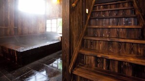 A wooden interior with a staircase, a bench, and a window allowing natural light.