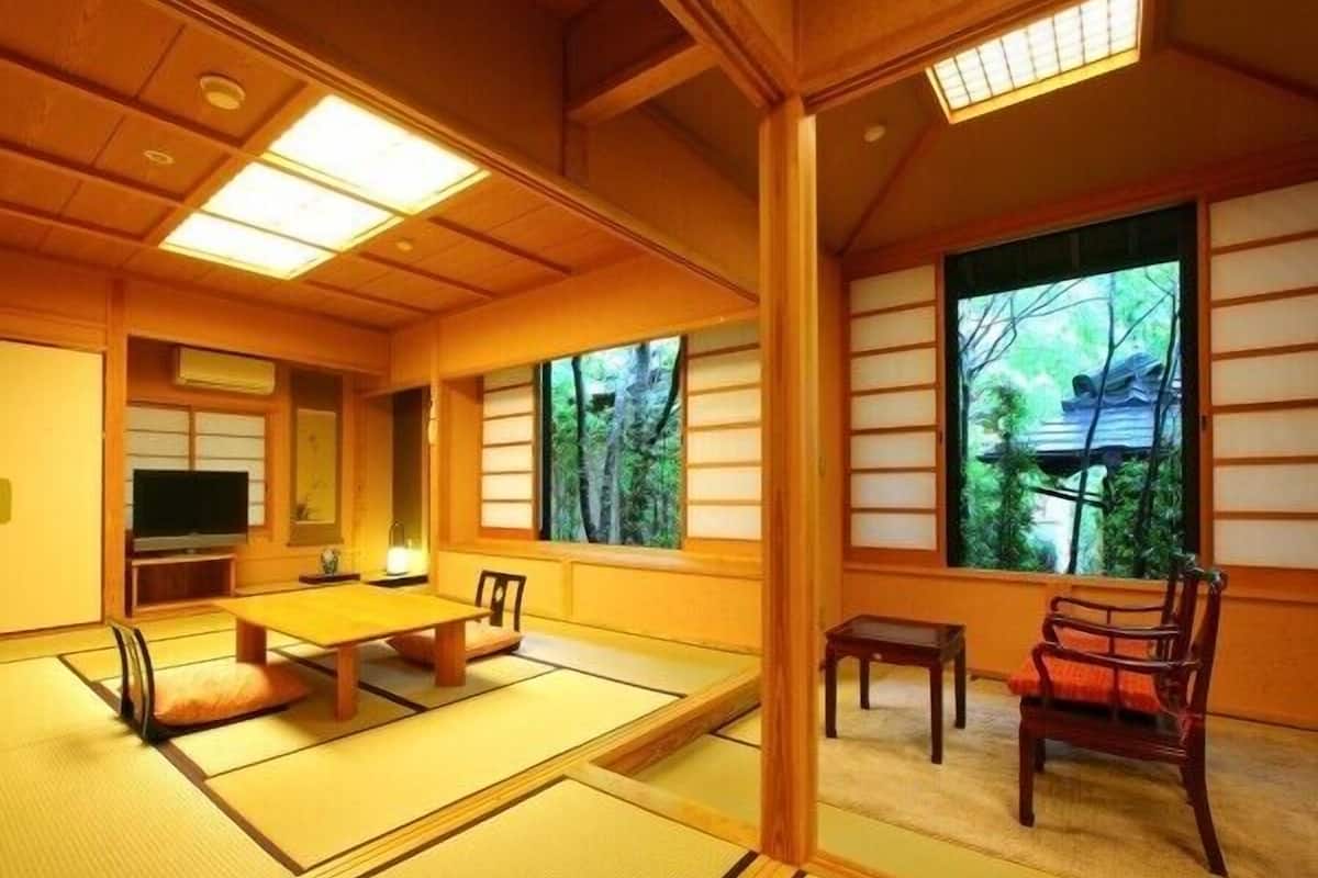 Una habitación japonesa tradicional con suelo de tatami, una mesa baja, televisor y puertas correderas.