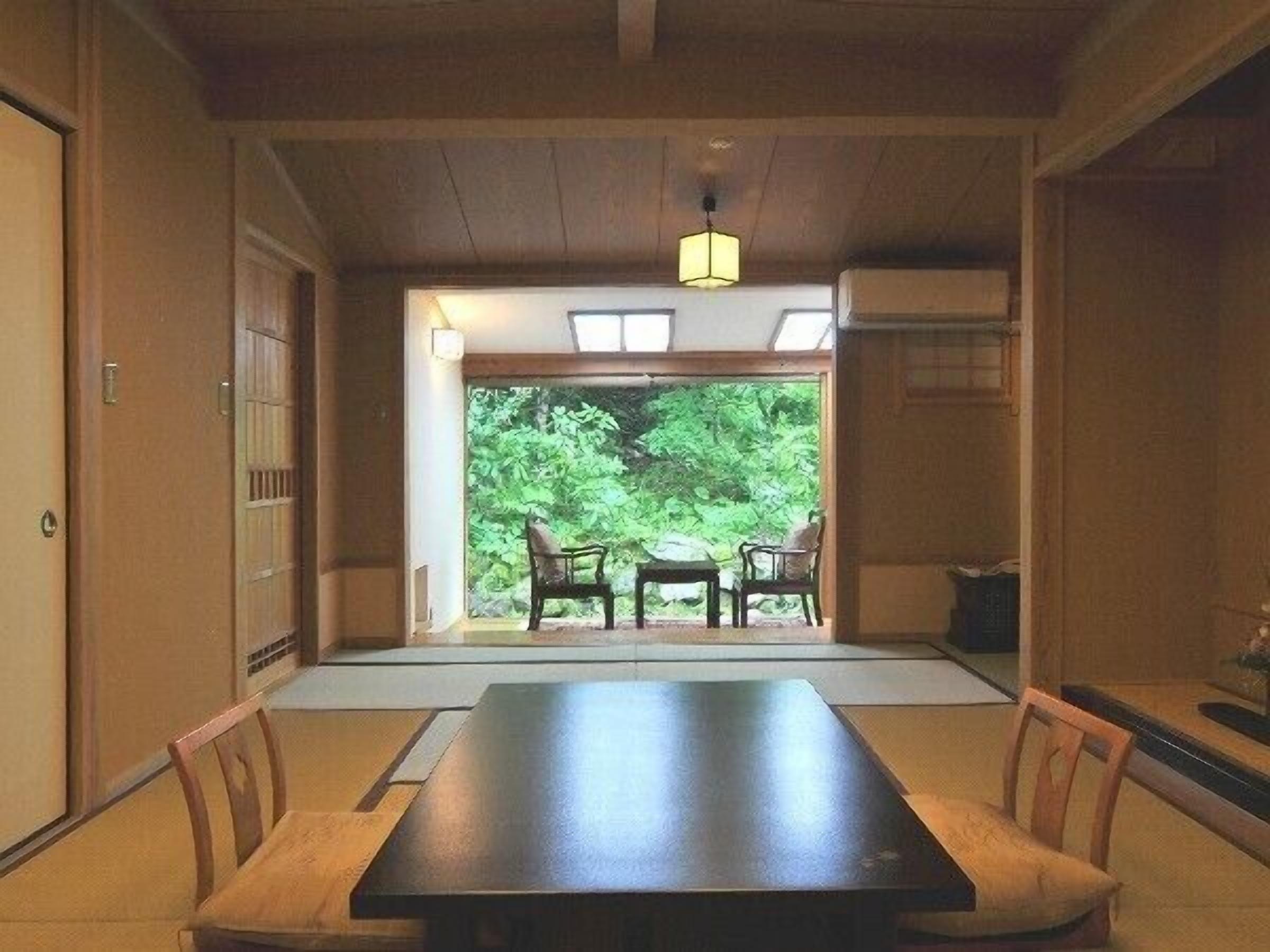 A traditional Japanese-style room with tatami flooring, a low table, and chairs.