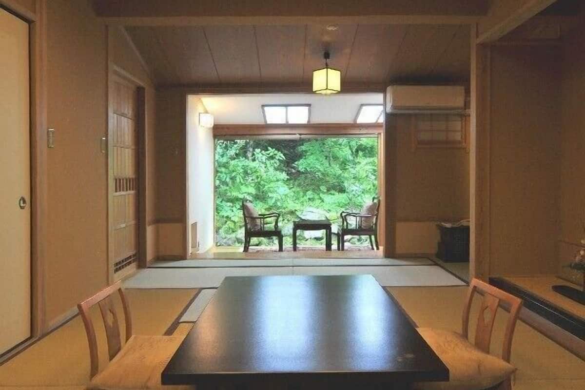 Una habitación tradicional japonesa con suelo de tatami, una mesa baja y sillas.