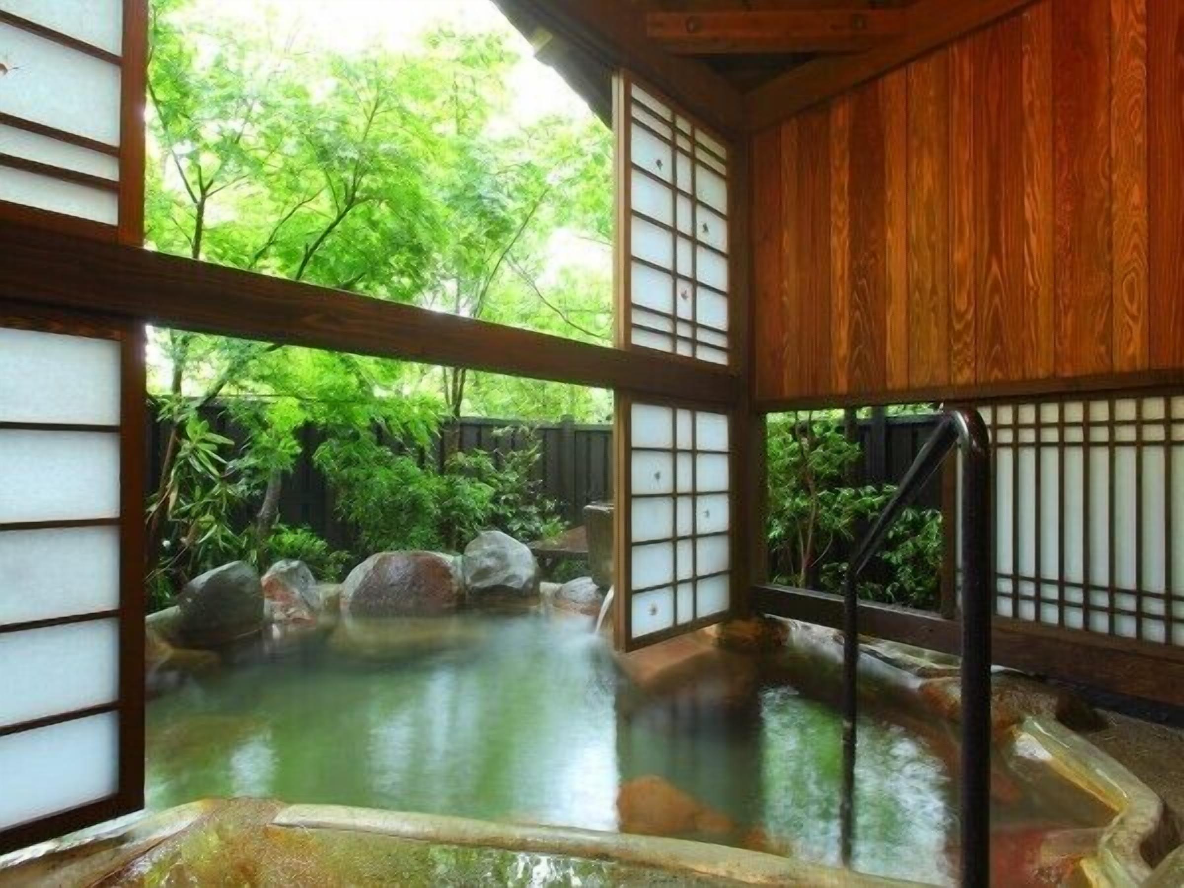 A traditional Japanese onsen with wooden sliding doors and a view of lush greenery.